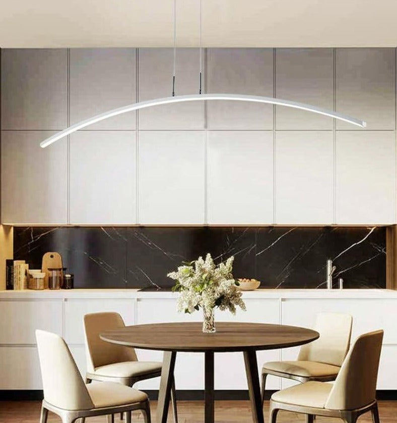WhiteLED pendant light with a curved design, installed over a dining table in a bright interior setting.