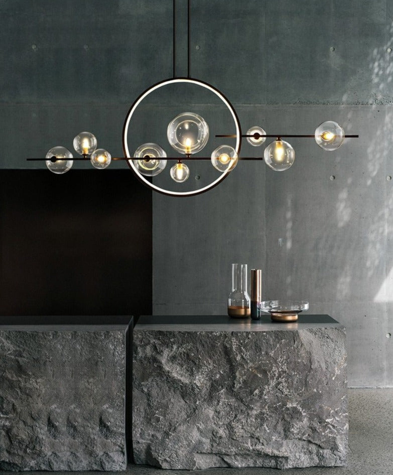 Modern pendant light with glass globes and a circular LED ring above a stone kitchen island.