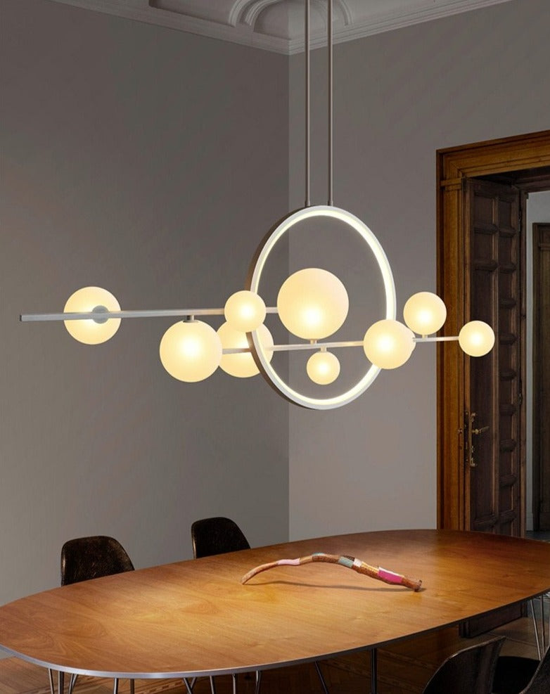 Modern pendant light with glass globes and a circular LED ring above a stone table.